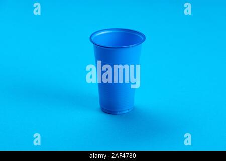 Blue empty plastic cup on a blue background. Recycling plastic. Plastic waste. Stock Photo