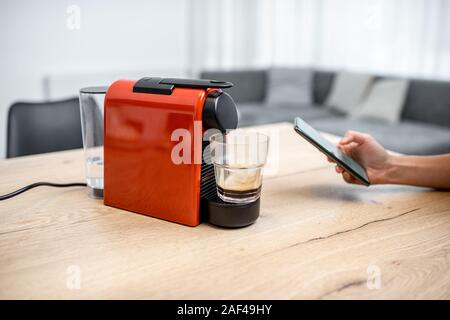 Modern coffee machine connected online with smartphone application. Concept of a smart home and mobile application for managing devices at home Stock Photo