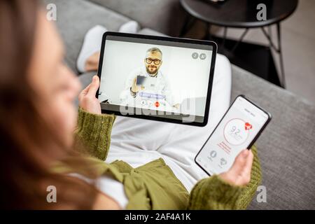 Woman making video call to a doctor using digital tablet, feeling bad at home. Concept of telemedicine and patient counseling online Stock Photo