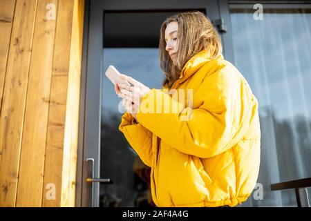 Woman locking smartlock on the entrance door using a smart phone. Concept of using smart electronic locks with keyless access Stock Photo