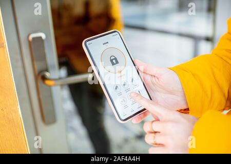 Locking smartlock on the entrance door using a smart phone remotely. Concept of using smart electronic locks with keyless access Stock Photo