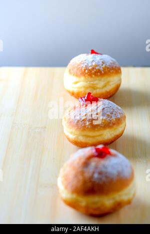 Chanukah celebration concept. Close up view of tasty donuts with jam on wood background. Hanukkah sweet traditional food. Stock Photo