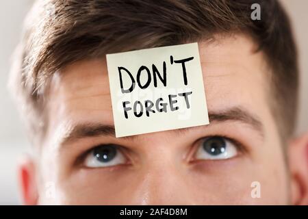 Sticky Note With Don't Forget Text Stuck On Forehead Of A Young Businessman Stock Photo