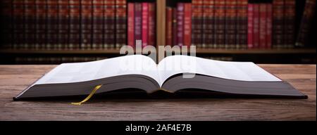 Open Law Book On Wooden Desk With Law Books In Background In Courtroom Stock Photo