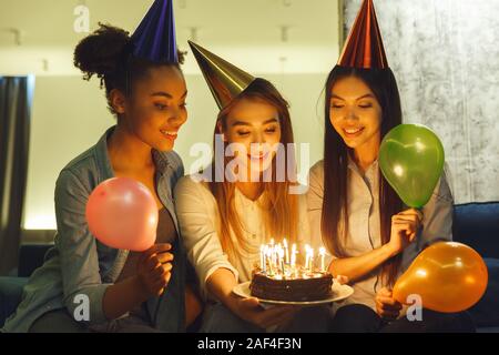 Group of friends having party indoors fun together celebrating birthday in the dark Stock Photo