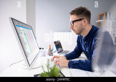 Side View Of Businessman's Hand Analyzing Data On Computer Over Desk Stock Photo