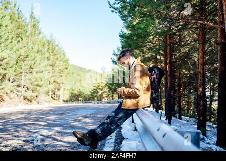 Tourist in the mountains doing auto stop with his cellphone Stock Photo