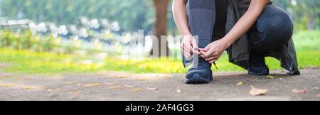 sporty women are tied with running shoes to run exercise in the morning. Portrait of beautiful Women exercising in the park on green tree and green gr Stock Photo