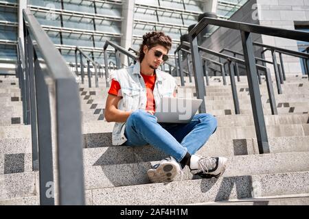Young adult man using modern laptop outdoor Stock Photo