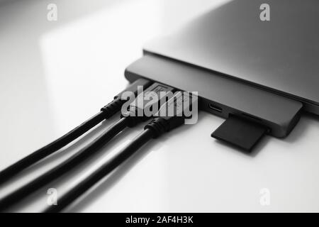 Laptop with USB Type-C adapter with pluged USB cables and SD card. The USB adapter under the Type-C connector for laptop. Multiport station for laptop Stock Photo