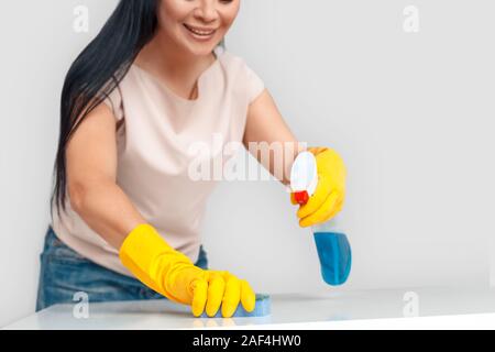 Freestyle. Asian woman in gloves standing isolated on white with spray cleaning surface with sponge close-up smiling joyful Stock Photo