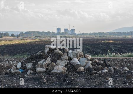 Little pile of rocks and soil, in the middle of a field, mountains in the background Stock Photo