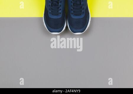 Classic blue sneakers on the yellow and grey background. Concept for healthy lifestyle and everyday training.  Place for text. Stock Photo