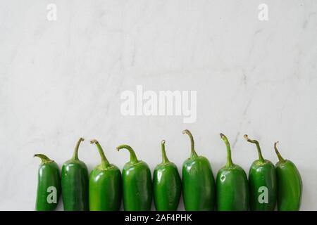 Bright green jalapeno peppers on a marble cutting board with copy space; food preparation Stock Photo