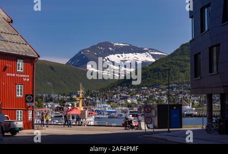 TROMSØ, NORWAY - people walking at harbour with mountains in distance. Stock Photo