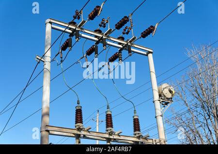 Closeup of high voltage overheard electrical power lines and insulators against a blue sky, Vancouver, BC, Canada Stock Photo