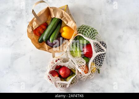 Vegetables and fruits in net and paper bags on white background Stock Photo