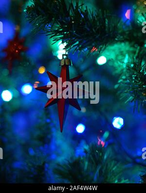 Red star hanging from Christmas tree. Bokeh. Concept : festive season. Stock Photo