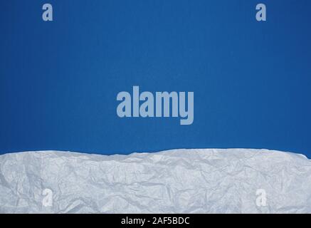 blue background with white crumpled torn paper elements, place for writing op in the middle, template Stock Photo