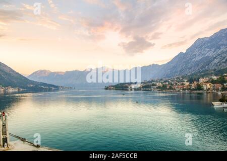 Morning sunrise highlights the mountains over the the Boka, or Bay of Kotor, in the emerald turquoise waters of the Adriatic Sea in Kotor, Montenegro Stock Photo