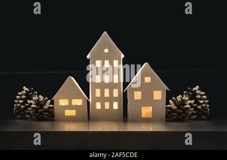 Beautiful winter landscape with small houses made of paper illuminated inside and with pine cones Stock Photo