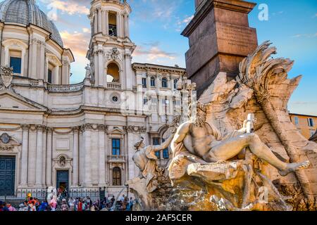 Tourists relax in the shade of the Sant'Agnese in Agone church in front of Bernini's baroque Fountain of the Four Rivers in Piazza Navona. Stock Photo