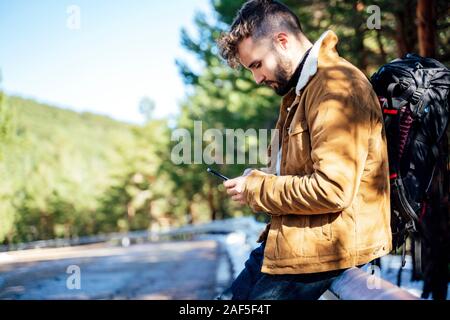 Tourist in the mountains doing auto stop with his cellphone Stock Photo