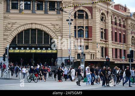 Pedestrians crossing Flinders Street, with the iconic Flinders Street Station entrance in the background. Stock Photo