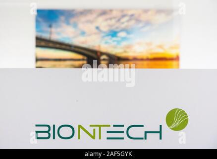 Mainz, Germany. 27th Nov, 2019. The company logo of the biotechnology company BioNTech stands in front of a photo of the Theodor Heuss Bridge. BioNTech boss Sahin expects significant improvements in the detection of cancer in the coming years. Credit: Andreas Arnold/dpa/Alamy Live News Stock Photo