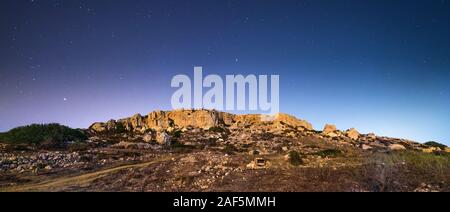 Cliff face at Mgiebah Bay in Malta, under a clear starry sky Stock Photo