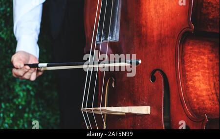 Cello player with focus on the hand, close up picture. Musician playing bass violoncello. Cellist hands playing orchestra music. Orchestra performing Stock Photo