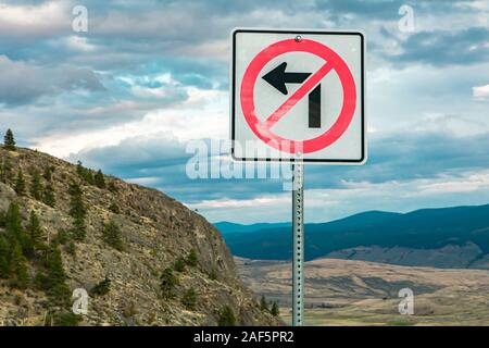 Do not turn left at the intersection, Regulatory road signs, on mountain high roads against nature and, mountains and cloudy sky Stock Photo