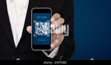 QR code scanning payment and verification. Businessman holding mobile smart phone scan QR code Stock Photo