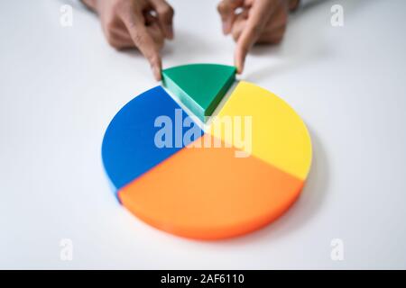 High Angle View Of Businessperson's Hand Placing A Last Piece Into Pie Chart Stock Photo