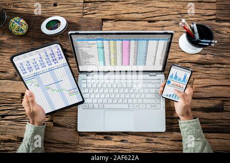 High Angle View Of Businessman Using Various Applications On Electronic Devices Over Desk Stock Photo