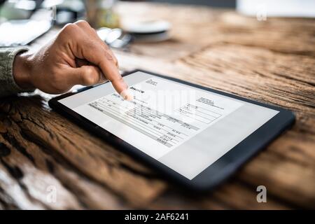 Close-up Of A Businesswoman's Hand Checking Invoice On Digital Tablet Stock Photo