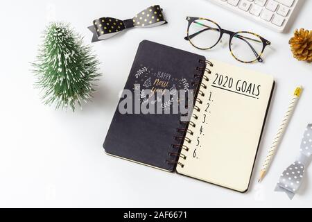 2020 New Year Resolution Goals List Concept. Business office desk with notebook written in handwriting about plan listing of new year goals and resolu Stock Photo