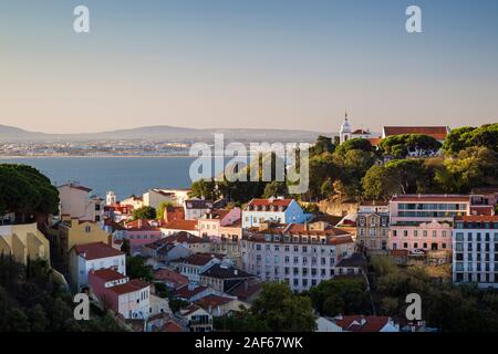 View of Tagus River, Church Santa Cruz do Castelo and old buildings at Alfama district in downtown Lisbon. Viewed from Miradouro da Senhora do Monte. Stock Photo