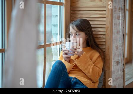 Cute girl looking out the window in the kitchen Stock Photo
