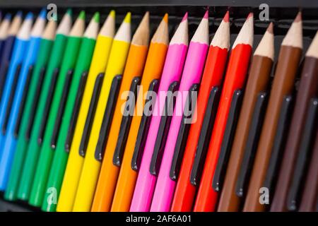 Set of bright wooden colored pencils laid out in a row with a dark background. Stationery background with an art and education Concept. Stock Photo