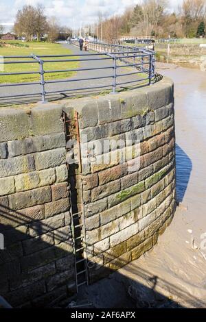 Old quayside wall and inset steel ladder wth nearby mooring points on a tidal section of the River Mersey near Spike Island, Widnes Cheshire. Stock Photo