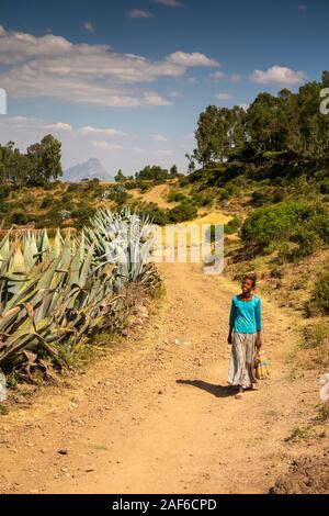 Ethiopia, Tigray, Axum (Aksum), Abalanicos, smiling girl walking along dusty rural road lined with huge aloe plants Stock Photo