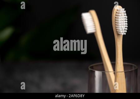 Eco natural bamboo toothbrushes in glass on black background . Sustainable lifestyle and zero waste home. bathroom essentials. Dental care and zero wa Stock Photo