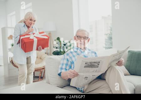Portrait of her she his he two nice attractive lovely cheerful cheery people granny carrying big large romantic gift for grandpa in light white Stock Photo