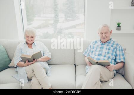 Portrait of her she his he two nice attractive focused cheerful cheery peaceful calm spouses reading novel interesting book in light white interior Stock Photo