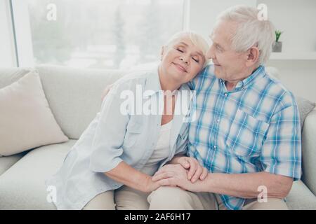 Portrait of her she his he two nice attractive lovely sweet gentle cheerful peaceful calm romantic spouses holding hands sitting on divan spending Stock Photo