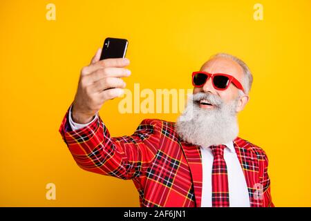 Closeup photo of cool grandpa white beard guy holding telephone taking funny selfies wear sun specs checkered red blazer tie outfit isolated yellow Stock Photo