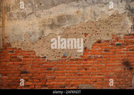 Vintage weathered brick wall with cement plaster finish, part of cement is cracked Stock Photo