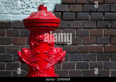 ornate old fire hydrant against the brick wall Stock Photo