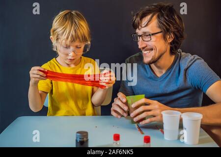 Father and son conduct chemical experiments at home. Home made slime. Family plays with a slime Stock Photo